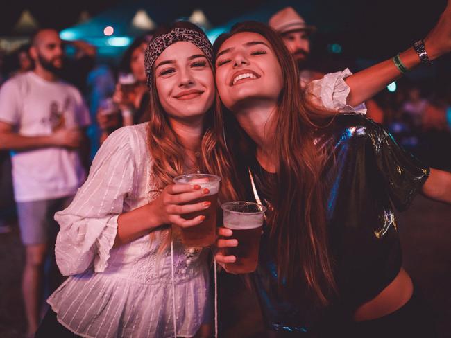 Two young women drinking beer and enjoying summer music festival  istock image