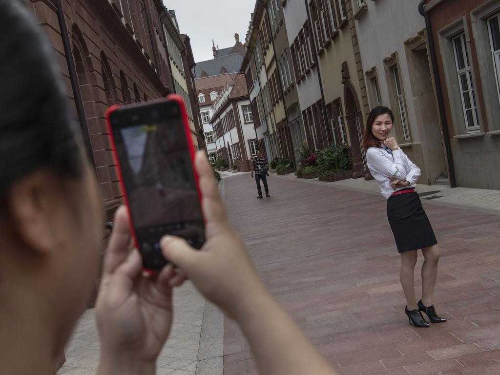 A woman poses for a picture taken by a friend in the campus’ idyllic streetscape. Picture: Getty