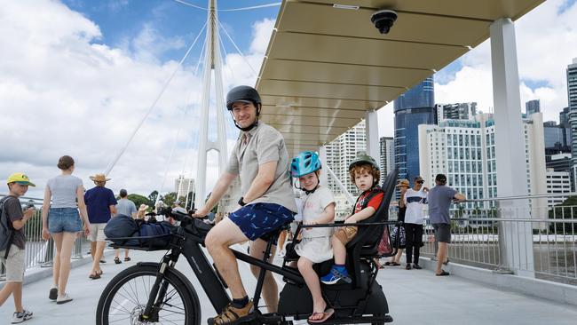 David Jeffery rides with kids Odette, 6, and Nicholas, 2, at the opening of the Kangaroo Point Bridge in Brisbane. Picture Lachie Millard