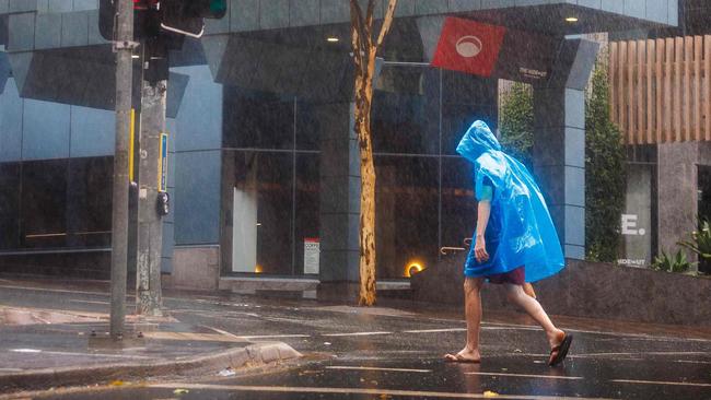 A man walks through the Central Business District (CBD) area of Brisbane on March 8, 2025, as cyclone Alfred crossed the southeast Queensland coast. Cyclone Alfred weakened into a tropical low on March 8 but still threatened to unleash major floods on swollen rivers as it approached the rain and wind-lashed eastern coast of Australia. (Photo by Patrick HAMILTON / AFP)