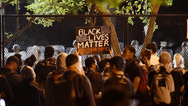 Demonstrators protesting the death of George Floyd hold up placards by the metal fence erected in front of the White House. AFP)