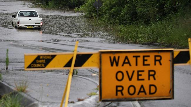 Two men try to drive through the flood waters after Burns Road, Ourimbah was closed due to severe flooding.