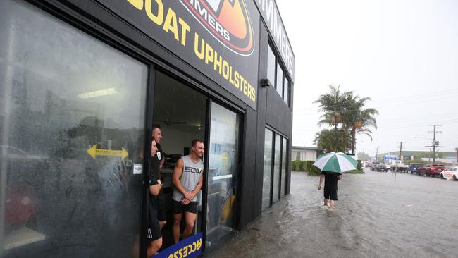 Major flooding in Currumbin Creek rd at Currumbin. Factory workers watch the crisis unfold in front of them. Picture: Glenn Hampson