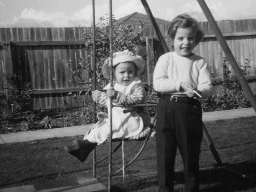 <p>Jane stands posing for dad while Arnna clutches at the swing on the back lawn.</p>