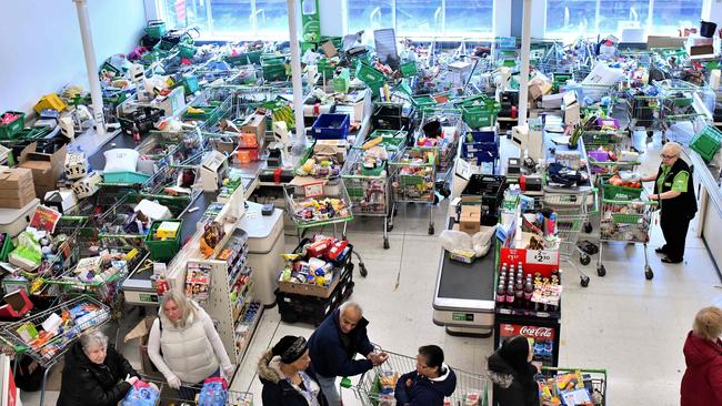 Trolleys piled high for delivery are seen as shoppers queue at the checkout of a supermarket in London on March 14.