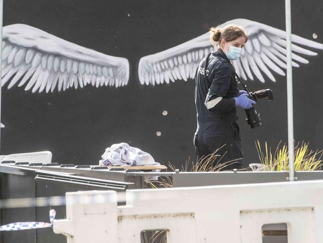 A forensic officer before a bullet-riddled wall at Sweet Lulu cafe. Picture: Tony Gough