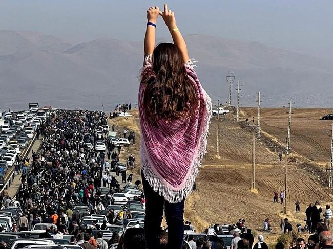 -- AFP PICTURES OF THE YEAR 2022 --  This UGC image posted on Twitter reportedly on October 26, 2022 shows an unveiled woman standing on top of a vehicle as thousands make their way towards Aichi cemetery in Saqez, Mahsa Amini's home town in the western Iranian province of Kurdistan, to mark 40 days since her death, defying heightened security measures as part of a bloody crackdown on women-led protests. - A wave of unrest has rocked Iran since 22-year-old Amini died on September 16 following her arrest by the morality police in Tehran for allegedly breaching the country's strict rules on hijab headscarves and modest clothing. (Photo by UGC / AFP) / AFP PICTURES OF THE YEAR 2022  === RESTRICTED TO EDITORIAL USE - MANDATORY CREDIT 