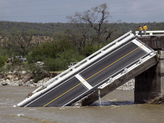 People stand on part of the collapsed Aduano bridge leading to Los Cabos.