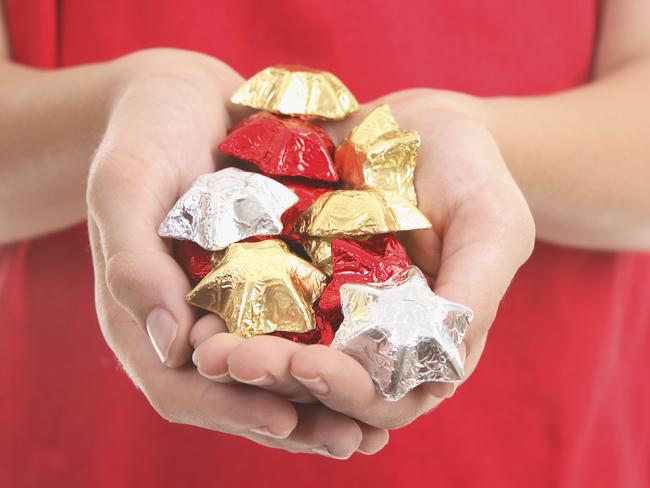 Cupped hands hold a handful of foil wrapped chocolate stars.