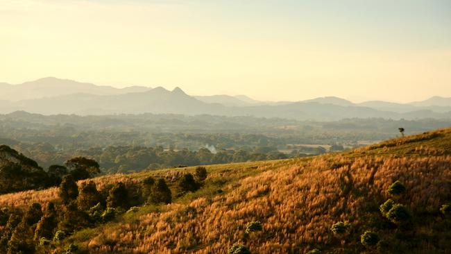 Horizontal landscape of the mountains, hills and plains of the Byron Bay Shire on the north coast of NSW. Late afternoon sunshine lights up the rainforests.