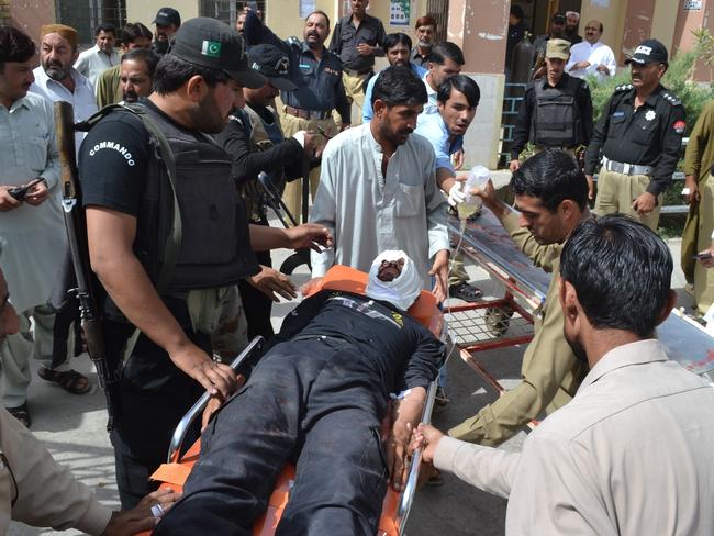Pakistani security officials rush their injured colleague to a hospital in Quetta, Pakistan, following an attack claimed by Islamic State.