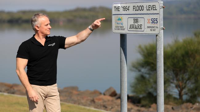 Kerry Plowright, of Aeeris, points to a sign next to the Tweed River showing the flood level in 1954 as a result of the 'Great Gold Coast Cyclone'.