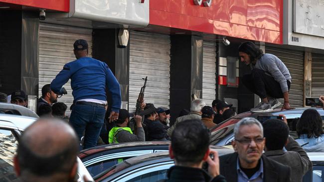 A gunman fires shots in the air to disperse clashing protesters from a rally called for by Syrian activists and civil society representatives ‘to mourn for the civilian and security personnel casualties’, and others from a counter-demonstration at al-Marjeh square in Damascus on Sunday. Picture: AFP