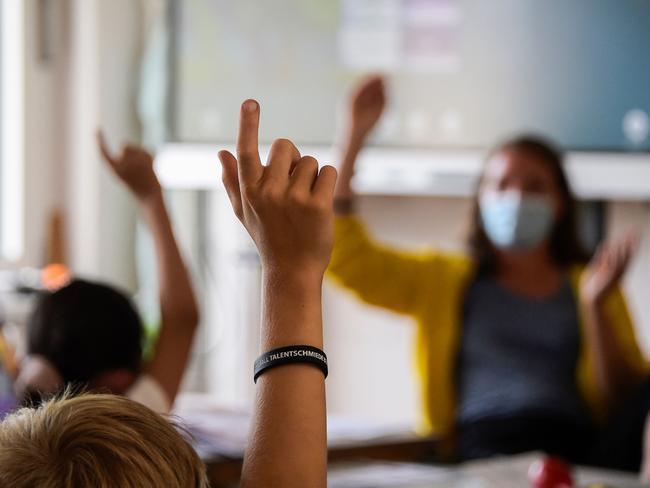 Pupils gesture towards their teacher as they attend a lesson at their elementary school in Berlin on August 9, 2021, after coming back from summer holidays and amid the coronavirus COVID-19 pandemic.. - Berlin's pupils are to wear face masks during the first two weeks after the summerholidays in order to prevent the spreading of the coronavirus. (Photo by Tobias SCHWARZ / AFP)