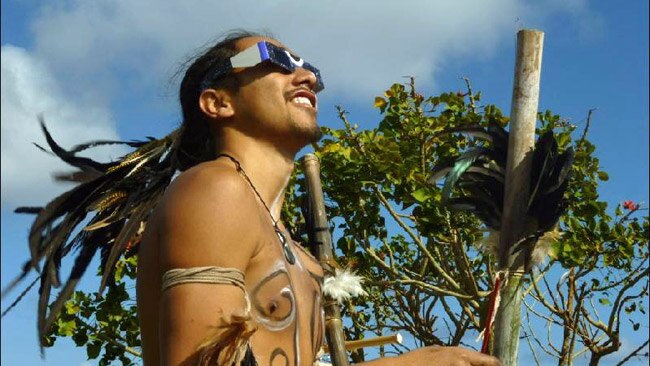 A Rapanuian man in traditional dress looks at the sun through his eclipse glasses. Picture: Angela Saurine