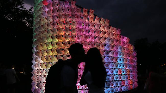 A couple sharing a kiss in front of a pig instalation. Picture: AAP Image/Steven Saphore