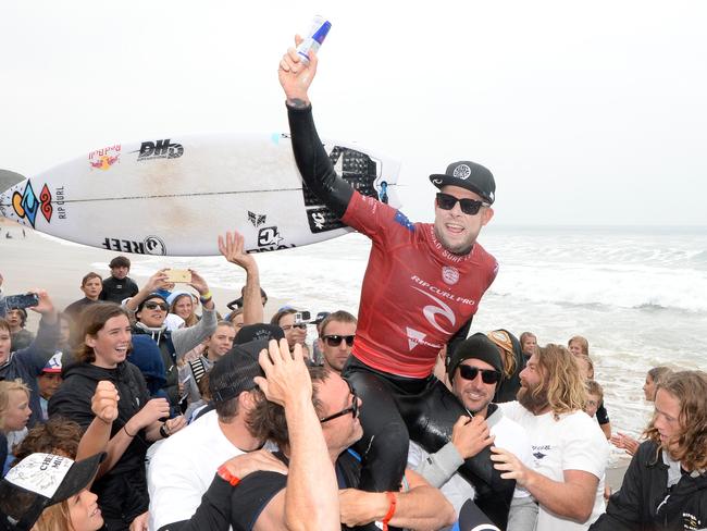 Mick Fanning leaves Bells Beach for the last time chaired up the beach by good friends Taylor Knox and Joel Parkinson. Picture: Jason Sammon