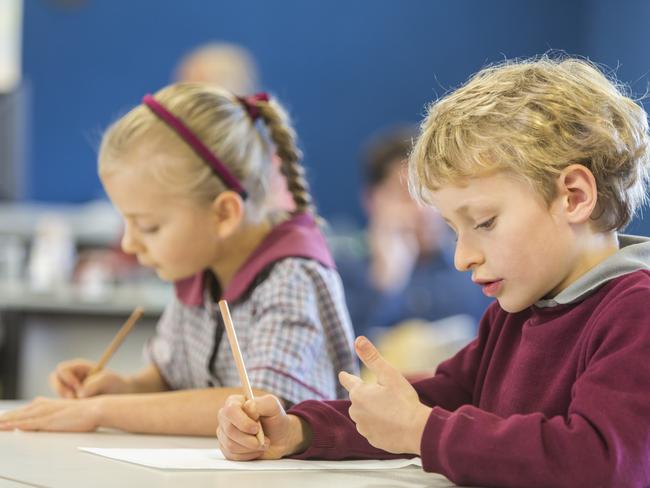 Happy young school boy in a classroom counting on his fingers