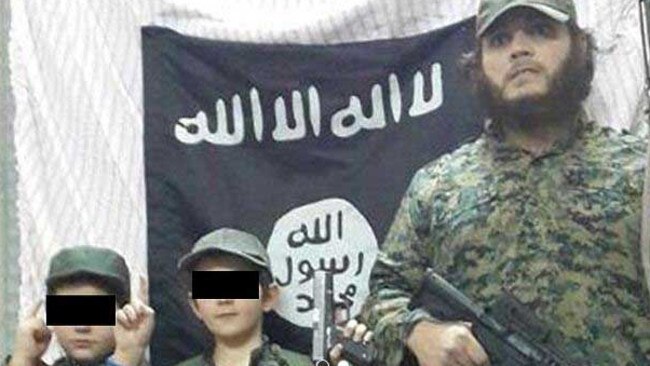 Khaled Sharrouf and boys believed to be his three sons (one not visible) stand in front of the Islamic State flag in an image posted on Twitter. Source: Supplied