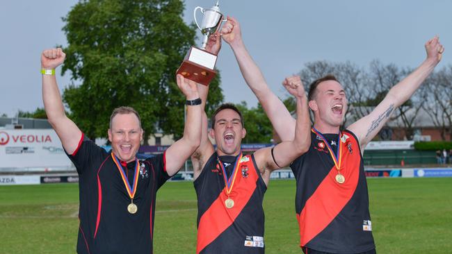 Tea Tree Gully coach Justin Maschotta, co-captains Chad Schoenmakers and Blake Penney lift the division two premiership trophy last season. Picture: Brenton Edwards