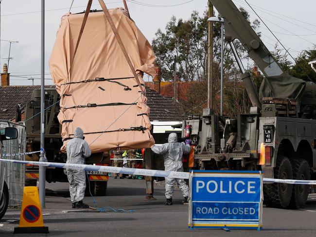 British Military personnel wearing protective coveralls work to remove a vehicle connected to the March 4 nerve agent attack in Salisbury, from a residential street in Gillingham, southeast England on March 14, 2018. Britain will expel 23 Russian diplomats over the nerve agent attack on former double agent Sergei Skripal and his daughter Yulia, in England, Prime Minister Theresa May told lawmakers today.  / AFP PHOTO / Adrian DENNIS