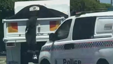 Screengrabs from a video in which a man was attempting to flee pursuing officers by jumping on the back of a moving truck in Townsville. The man was allegedly involved in an earlier incident at a shopping centre in Pimlico.