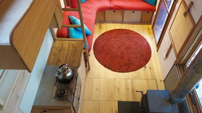 The interior has all the space-saving tiny home touches and a small wood fire. Picture: Supplied/Glampinghub.com