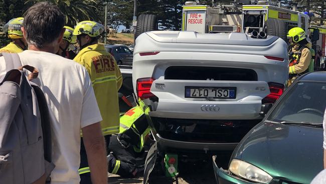 Emergency services work to remove an injured elderly driver from his overturned car on Barrenjoey Rd, Avalon Beach. Witnesses said the car flipped after hitting two parked cars. Picture: WWW.MATRIXNEWS.COM.AU