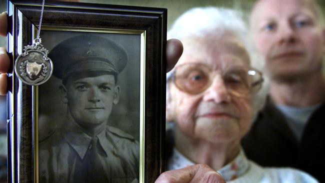 Lilian Chitty with her son Roger, holding the 'makeshift Brownlow Medal' made in Changi WWII prison which her husband Peter.