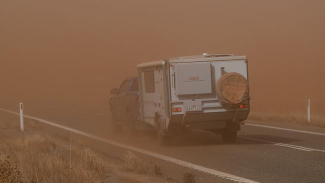 A car and caravan head into wall of dust on the Barrier Highway near Whyte Yarcowie. Picture Mark Brake