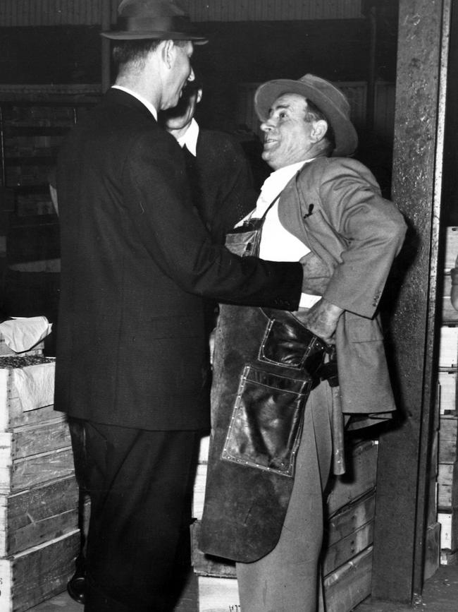 A police officer checks a Victoria Market stallholder for concealed weapons in 1964.