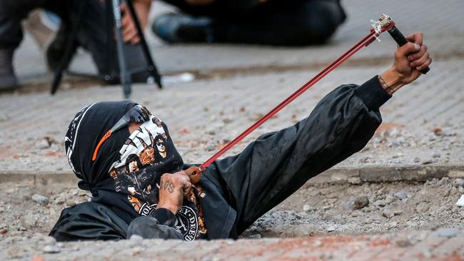 A Chilean feminist activist uses a slingshot during a protest in Santiago against gender violence and an entrenched political elite. Picture: AFP