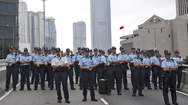 Policemen stand guard on a road as protesters march toward the Legislative Council after they continue to protest against the extradition bill in Hong Kong.