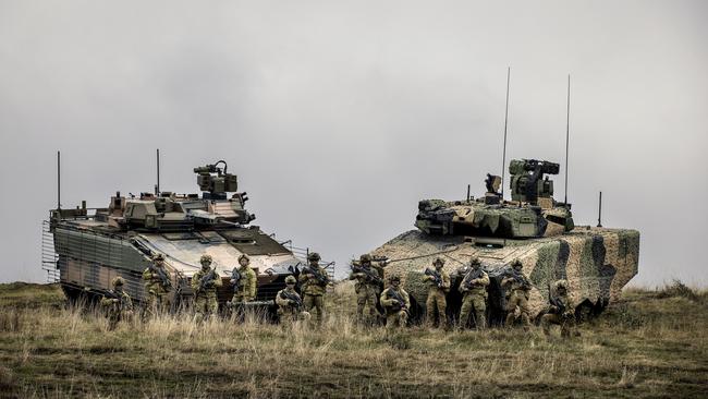 Australian Army soldiers stand with Hanwha Defence Australia Redback Infantry fighting vehicle (left) and Rheinmetall Lynx KF4 Infantry Fighting Vehicle (right) during evaluation trials.