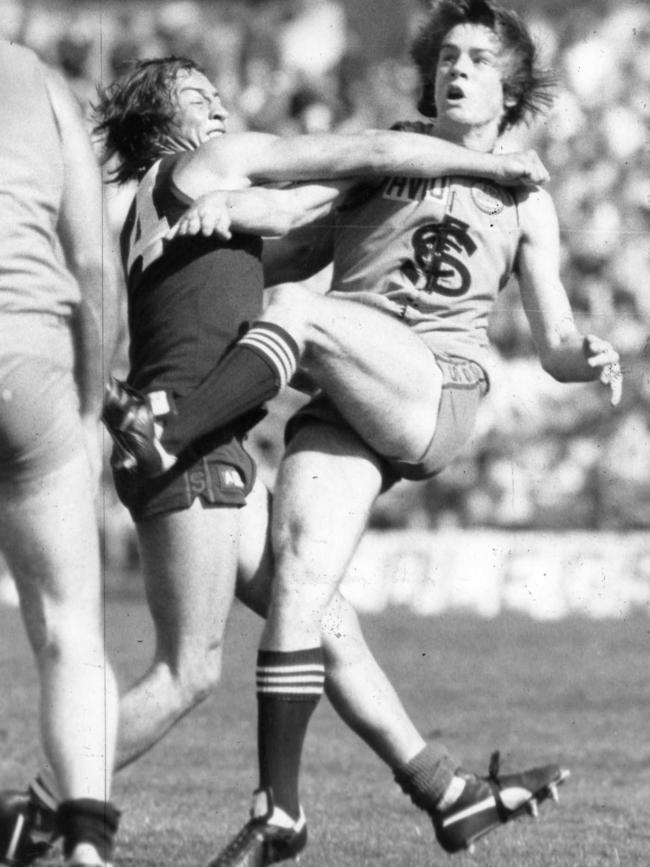 Motley cops some attention from Norwood champ Garry McIntosh as he kicks for goal in 1982.