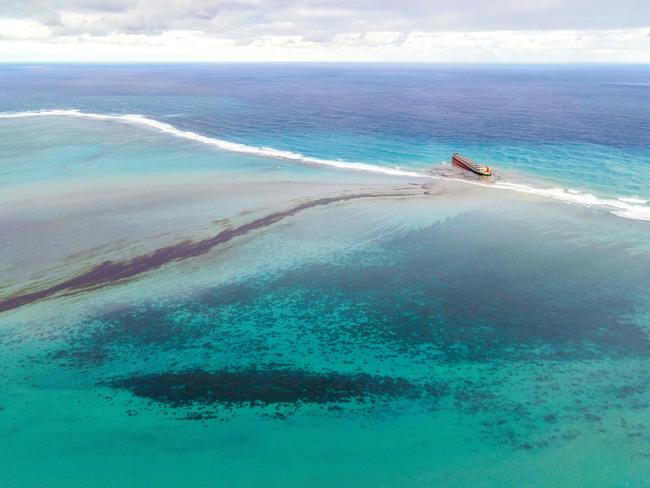 TOPSHOT - This aerial view taken on August 6, 2020 shows a large patch of leaked oil and the vessel MV Wakashio (R), belonging to a Japanese company but Panamanian-flagged, that ran aground near Blue Bay Marine Park off the coast of south-east Mauritius. - France on August 8, 2020 dispatched aircraft and technical advisers from Reunion to Mauritius after the prime minister appealed for urgent assistance to contain a worsening oil spill polluting the island nation's famed reefs, lagoons and oceans. Rough seas have hampered efforts to stop fuel leaking from the bulk carrier MV Wakashio, which ran aground two weeks ago, and is staining pristine waters in an ecologically protected marine area off the south-east coast. (Photo by STRINGER / AFP)