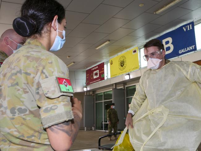 Australian Army nurse Captain Chanel Aguilar (left) supervises Lance Corporal Lachlan Scott as he dons personal protective equipment during the Australian Defence Force support to aged care introductory training at RAAF Base Edinburgh in South Australia.