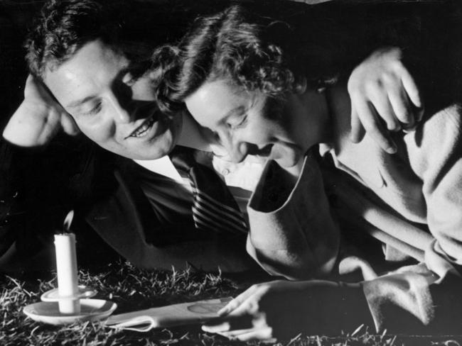 A couple relaxes during Carols by Candlelight in 1950. Christmas.