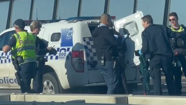 A man is escorted into a divvy van by police.