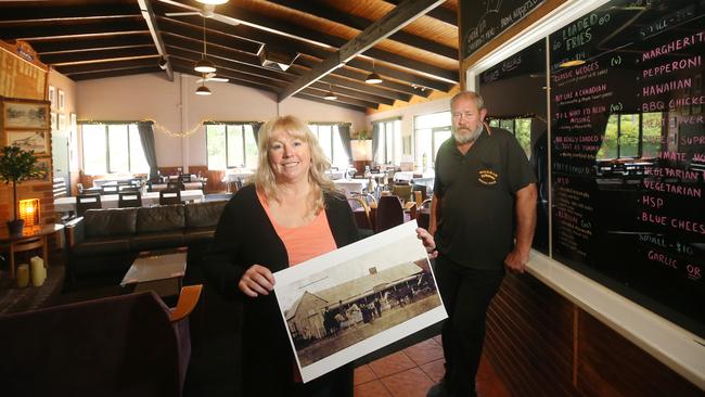 Jane Rowe and her husband Alan Bowles inside the Swifts Creek pub with a picture of the original Junction Hotel. Picture: Yuri Kouzmin