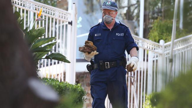 A policeman removes rocks from near the pool area. Picture: Hollie Adams