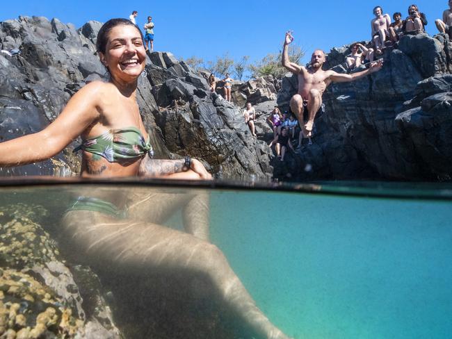 27 year old Lauren Nardone from New York cools off in rock pools at Granite Bay as Will Peregrine 23, from Brussels makes a splash as summer conditions hit the Queensland Coast. Photo Lachie Millard