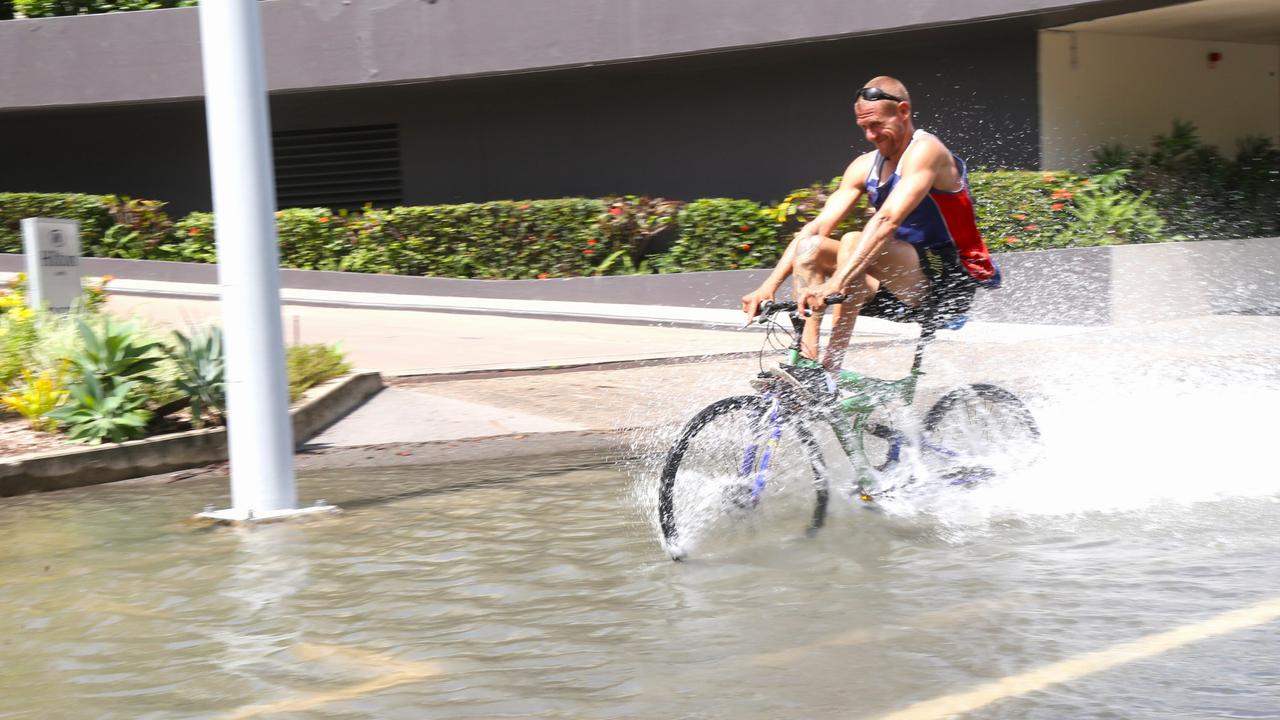 Shane Walford rides through king tide water outside the Harbour Lights complex on Marlin Parade in the Cairns CBD. Picture: Peter Carruthers