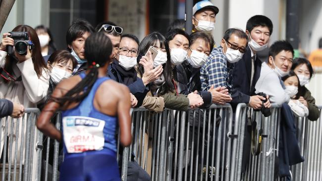 Spectators wearing masks watch a runner compete in the Tokyo Marathon on Sunday Picture: AP