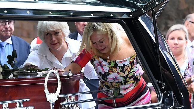 A distraught Kerri-Anne Kennerley places her hand on the casket following the funeral for her husband John Kennerley. Picture: AAP