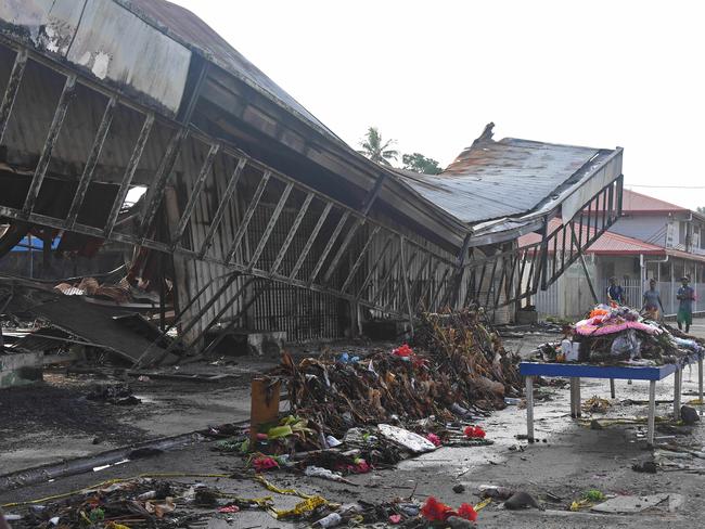 Floral tributes to 10 people who died in a suspected arson attack sit outside the remains of what was the island’s largest retail store. Picture: Brian Cassey