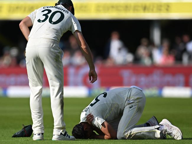 Australia's Pat Cummins (L) checks on Australia's Mitchell Starc (R) who has hurt his shoulder in the field. (Photo by Oli SCARFF / AFP)