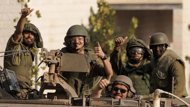 Israeli soldiers give a thumbs-up gesture as forces move near the border with Gaza on Saturday. Picture: Getty Images