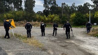 Police search an area near the intersection of Wakefield and Sugarloaf Range roads near Freemans Waterhole -m the place where they suspect a Nomads bikie gang nominee was shot.