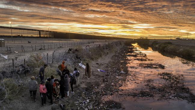 Immigrants wait next to razor wire after crossing the Rio Grande into El Paso, Texas. Picture: John Moore/Getty Images